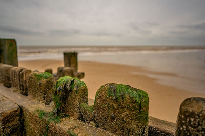 Close-up of rusty metal on beach against sky