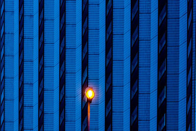 Illuminated street light against building at night