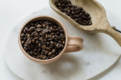 Coffee mug and wooden scoop with whole coffee beans