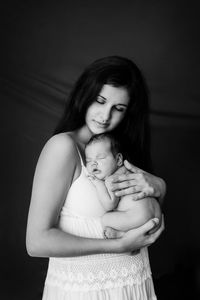 Portrait of mother and daughter against black background