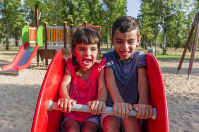 Two kids having fun playing together on a playground in a park.