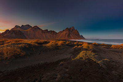 Scenic view of land and mountains against sky during sunset