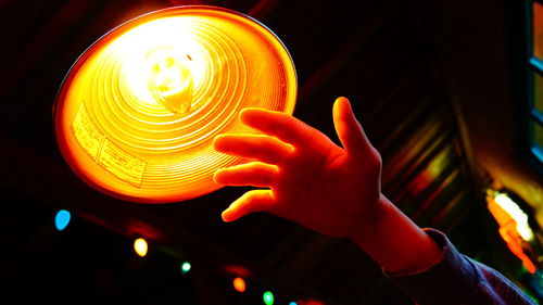 Cropped image of hand by illuminated pendant light at home
