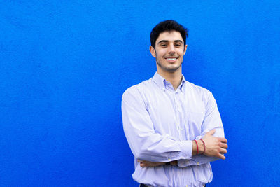 Portrait of a smiling young man against blue background