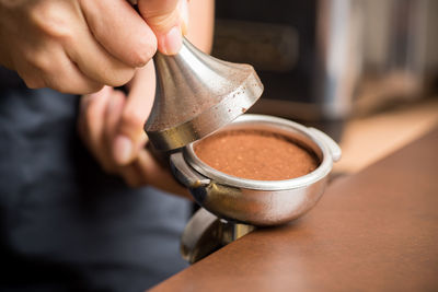 Cropped hand holding brown sugar in container