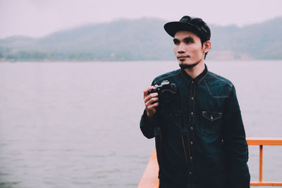 Man holding camera by lake