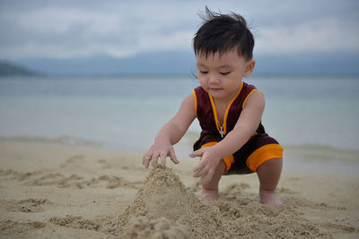 Boy playing on beach against sky