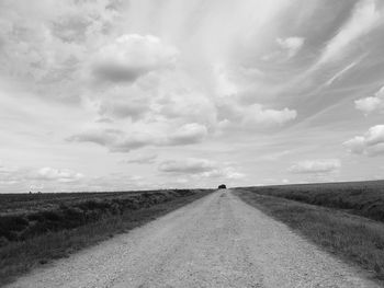 Road amidst field against sky