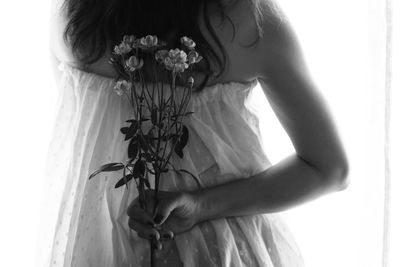 Rear view of woman holding flowers against white background