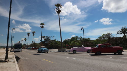 Cars parked on road against sky in city