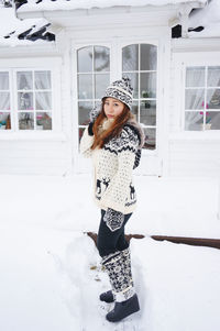 Portrait of smiling young woman standing in snow