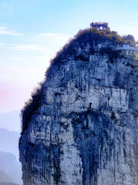 Rock formation by tree against sky