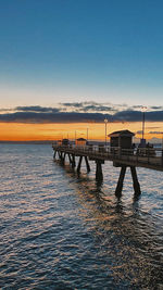 Pier over sea against sky during sunset