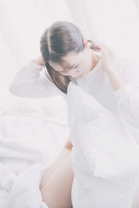 High angle view of young woman sitting on bed at home