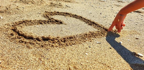 Low section of person walking on sand at beach