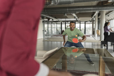 Happy businessman playing table tennis in office