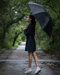 Full length of young woman with umbrella standing in park