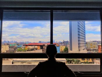 Rear view of man in city against sky