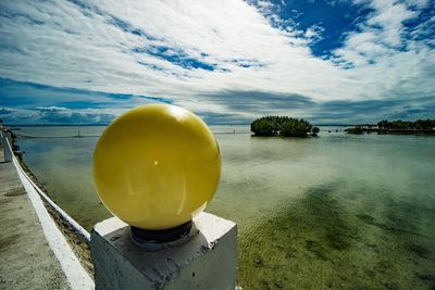 Yellow container on beach against sky