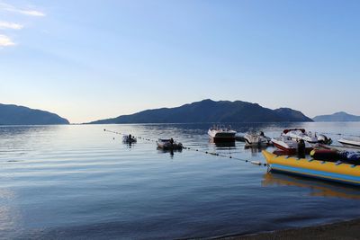 Boats moored in sea against blue sky