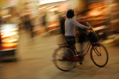 Blurred motion of man riding bicycle at night