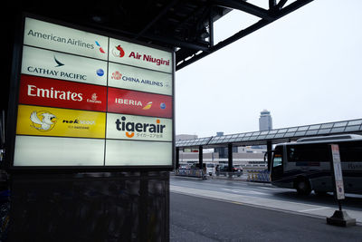 Information sign at railroad station in city against sky