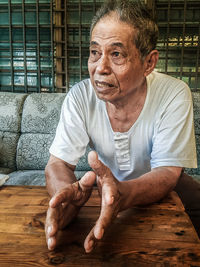 Senior man sitting on table at home