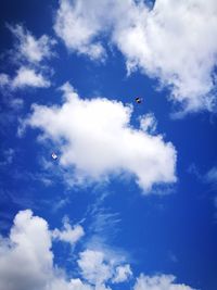 Low angle view of parachutes against blue sky