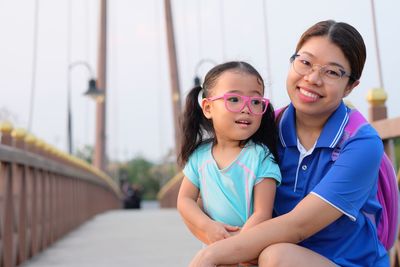 Portrait of smiling mother with daughter on footbridge
