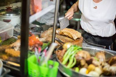 Midsection of woman cutting meat