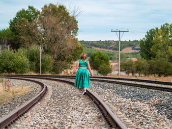 Rear view of woman walking on railroad tracks