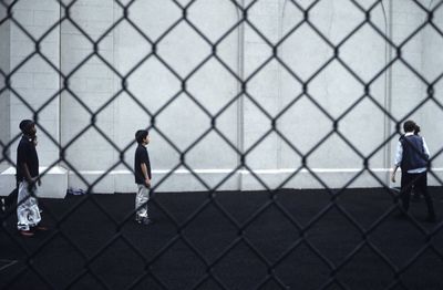 Full length of woman standing on chainlink fence