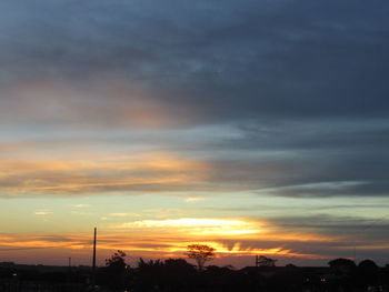 Silhouette of trees against dramatic sky during sunset