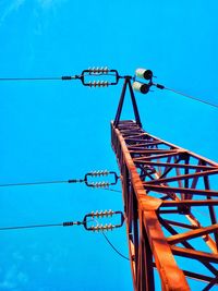 Low angle view of electricity pylon against clear blue sky