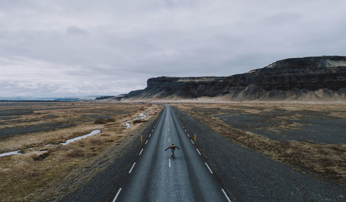 Aerial view of man skateboarding on road against sky and mountain