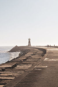 Lighthouse on beach against clear sky