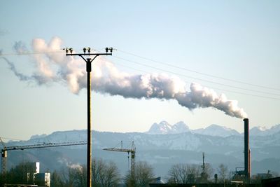 Smoke emitting from chimney against sky