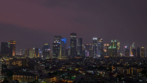 Illuminated buildings in city against sky at night