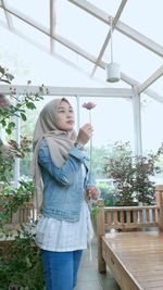 Young woman holding flower at home