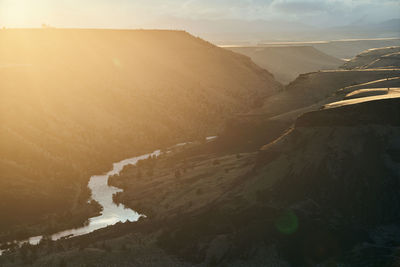 River winding through desert canyon at sunset with sun flare