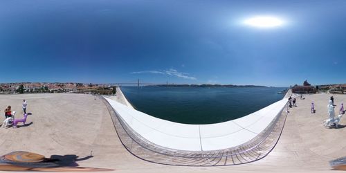 Panoramic view of people by sea against blue sky