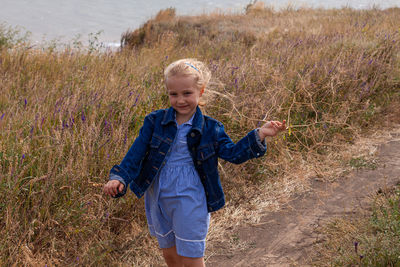 Blond long hair child girl in denim jacket walks on sea landscape. travelling hiking running outdoor