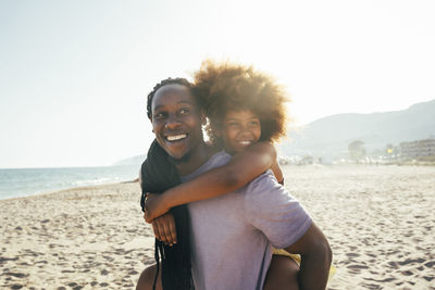 Happy father piggybacking daughter at beach