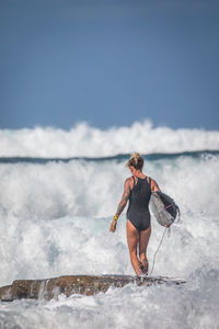 Rear view of woman on sea shore against sky