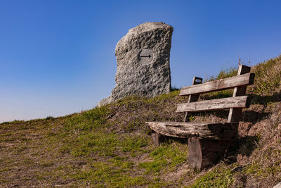 A wooden bench and a granite sign invite you to rest