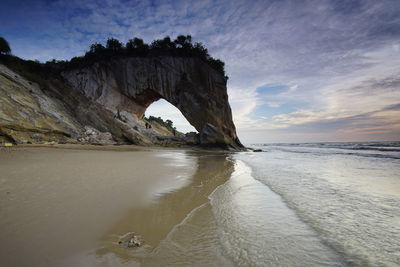 Rock formation on beach against sky