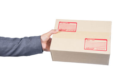 Close-up of hand holding box against white background
