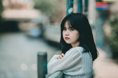 Portrait of young woman looking away in city