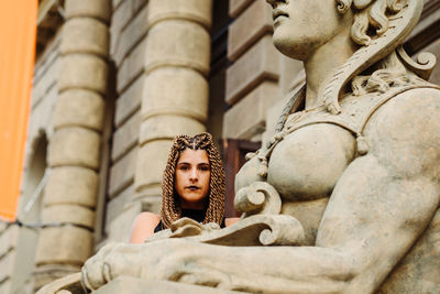 Portrait of woman by statue against historic building