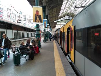 People waiting at railroad station platform in city